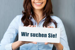 Junge Frau mit einem Schild auf dem "Wir suchen Sie!" steht