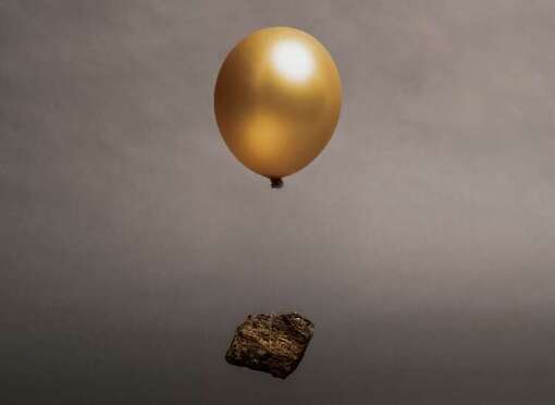 Stein hängt an goldenem Luftballon