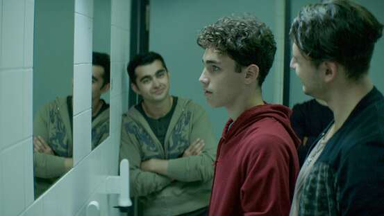 Filmszene Kippa. Drei junge Männer auf einer Scjhultoilette