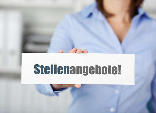 Eine Frau hält ein Schild mit dem Schriftzug "Stellenangebote"