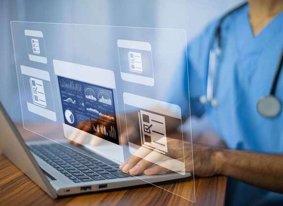 Krankenschwester sitzt am Laptop zwecks Patientendokumentation
