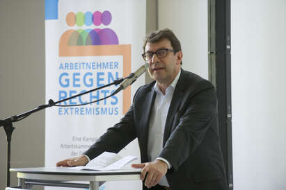Vorstandsvorsitzender (2015) Hans-Peter Kurtz redet auf einer Veranstaltung "arbeitnehmer gegen rechts" Vorstandsvorsitzender (2015) Hans-Peter Kurtz am Rednerpult vor einem Plakat mit dem Slogan "arbeitnehmer gegen rechts"