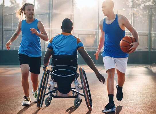 Rollstuhlfahrer nd zwei nicht Behinderte Menschen beim Ballsport