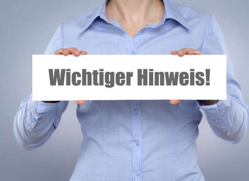 Frau, die ein Schild in den Händen hält, das mit "Wichtiger Hinweis" beschriftet ist
