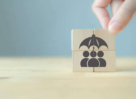 Ein Holzwürfel auf der der Icon-Figuren, die einen Regenschirm halten gemalt sind.