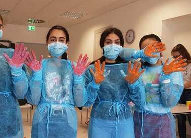 Schüler in medizinischer Kleidung, die die Hände hoch halten