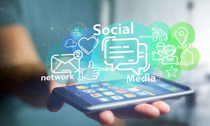 Eine Person hält Smartphone in der Hand auf dem Cloud Wolken mit Soccial Media Icons aufsteigen