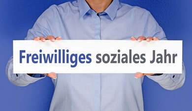 Freiwilliges soziales Jahr Person, deren Gesicht nicht sichtbar ist und die ein Schild mit der Aufschrift "Freiwilliges Soziales Jahr" in die Kamera hält