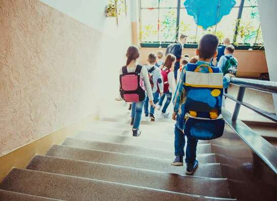 Adobe Stock Foto: Schulkinder, die in der Schule eine Treppe herunterlaufen